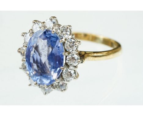 Sapphire and diamond 18ct yellow and white gold set cluster ring, the oval mixed cut sapphire measuring approx 13mm x 9.5mm, 