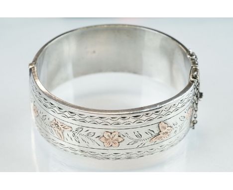 Silver hinged bangle, rose gold butterfly and flower head decoration in low relief; engraved repeating decoration, width appr
