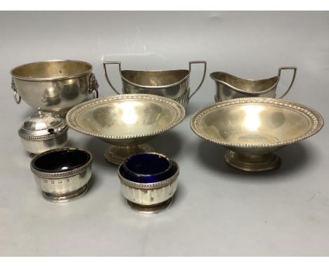   A pair of George V silver pedestal nut dishes, a small silver bowl with lion mask handles, a silver cream and sugar and a t