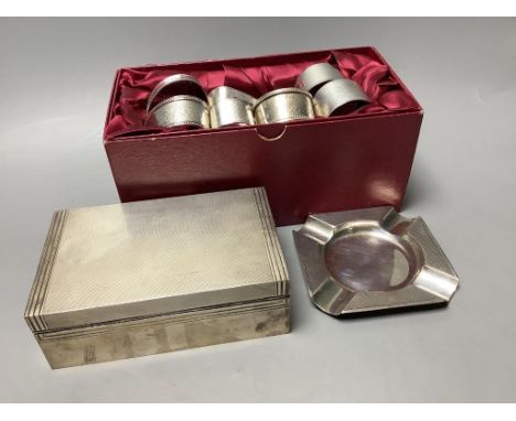   A presentation engine-turned silver cigarette box, a similar ashtray and a collection of silver napkin rings,variously engi