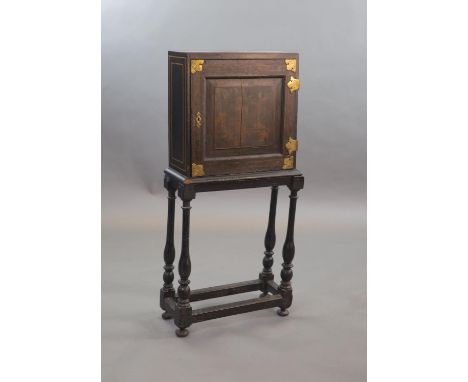   An early 18th century European japanned cabinet on stand,the single panelled door with gilt brass mounts, decorated with a 