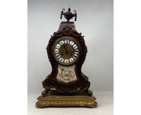 A Boulle work Mantel Clock having urn finial, the circular dial with enamel panels marked with Roman Numerals above a  panel 