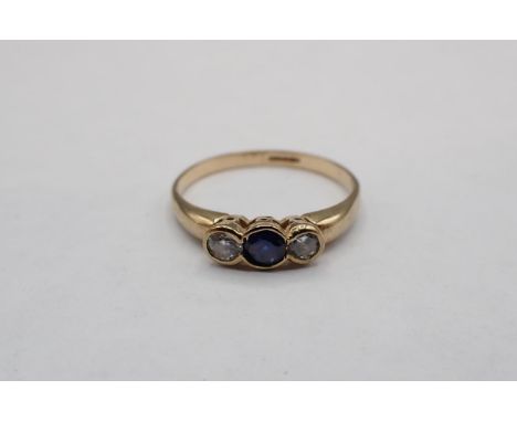 A Sapphire and Diamond three stone Ring rubover-set round sapphire between two brilliant-cut diamonds in 9ct gold, ring size 