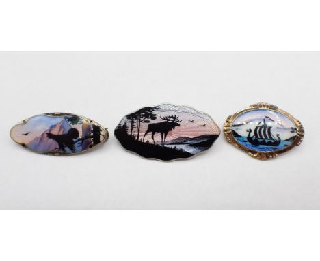 Three Norwegian silver and enamel Silhouette Brooches depicting; cockerel crowing 40mm wide, reindeer by lake at sunset 43mm 