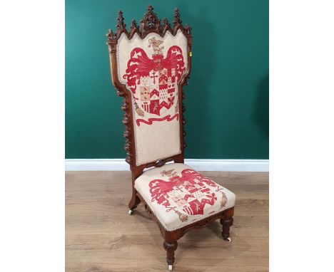 A Victorian Gothic Revival walnut framed Prayer Chair with cream cushioned upholstery decorated with Armorial Plaques, mounte
