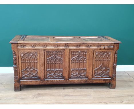 An oak Coffer with hinged panelled cover and four gothic carved tracery panels to the front, flanked by carved figures to the