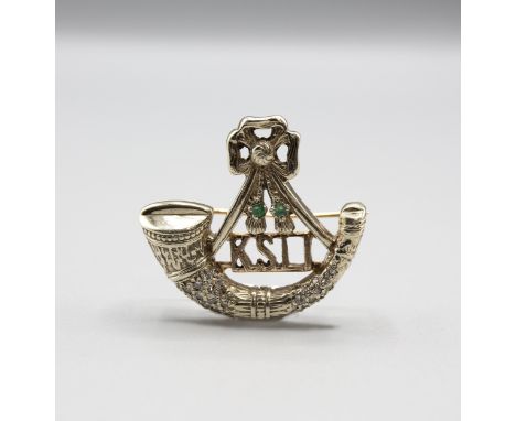A King's Shropshire Light Infantry Sweetheart Brooch formed as a bugle pavé-set eight-cut diamonds and two round emeralds in 