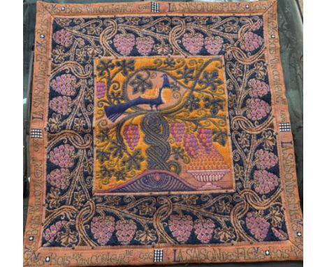 A tapestry panel the centre square depicting a peacock and vases of fruits in oranges and blues, 91 x 93cm