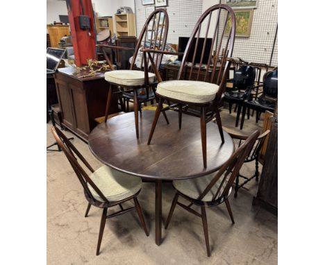 An Ercol dining table of circular form with drop flaps together with a set of four stick back chairs 