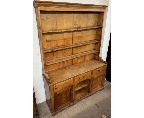 A large pine dog kennel dresser with a moulded cornice above three shelves, the base with a planked top above three drawers, 