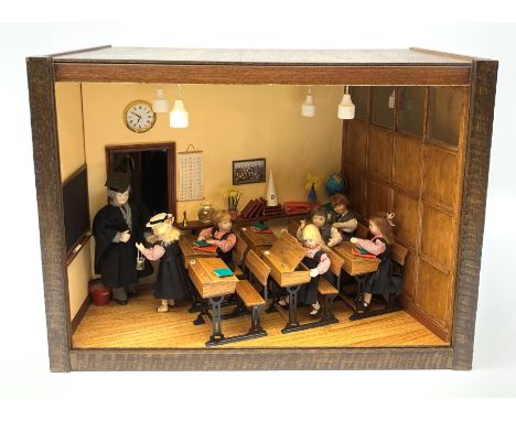 A 1/12th scale diorama of a school room interior, depicting pupils and teacher, the room furnished with panelled wall, desks,