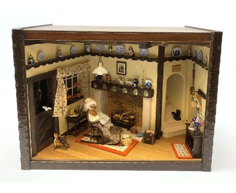 A 1/12th scale diorama of a cottage sitting room, depicting an elderly lady seated before a fireplace knitting, with dog and 