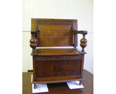 A circa 1930's oak monk's bench with bulbous supports to side arms and blind fret carving to top.