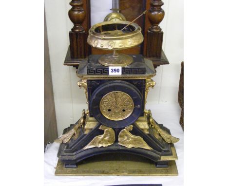 An Empire style slate mantel clock with ornate brass urn to top, metal figure mounts to front and animal heads to side on bra