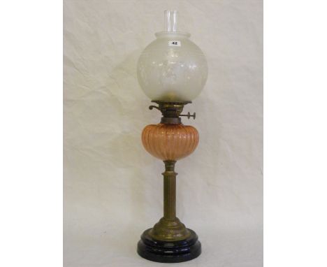A Victorian oil lamp with etched opaque glass shade above a pink glass reservoir over a circular brass column. 