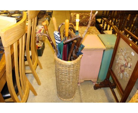 A wicker stick stand and contents of various walking sticks and umbrellas