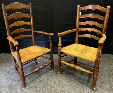 An early 19th century oak ladder back farmhouse kitchen chair, outswept arms, woven rush seat, turned stretchers and supports