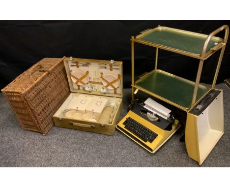 A mid 20th century picnic set;  a wicker hamper;  a gilt two tier trolley;  a typewriter (4) 