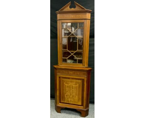 A Sheratan revival inlaid mahogany floor standing corner cabinet, shaped pediment above single astragal glazed door, protrudi