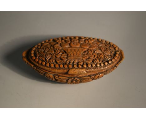 An 18th century coquilla nut oval snuff box, the cover carved with a basket of fruit, the base with a trophy regalia, 9cm wid