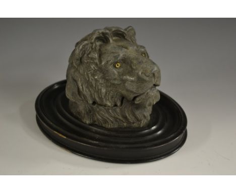 A late 19th century spelter novelty inkwell, cast as a lion's head, hinged cover, oval ebonised base, glass eyes, 22cm wide, 