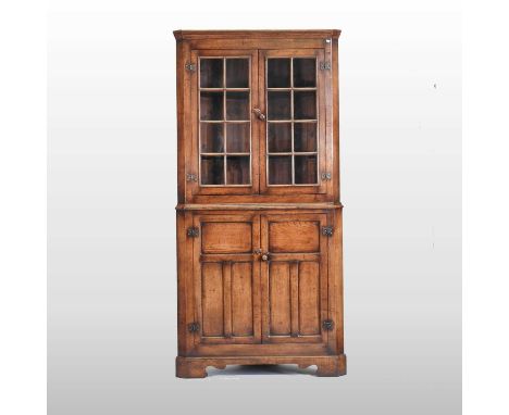 A large oak standing corner cabinet, 20th century, with a glazed upper section and panelled doors below, on shaped bracket fe
