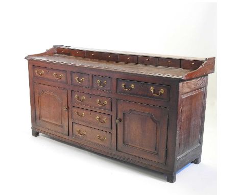 An 18th century Welsh oak and mahogany crossbanded dresser base, the back fitted with eight spice drawers, containing an arra