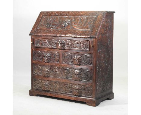 A 19th century heavily carved dark oak bureau, decorated with a green man, scrolls and masks, on bracket feet94w x 46d x 107h