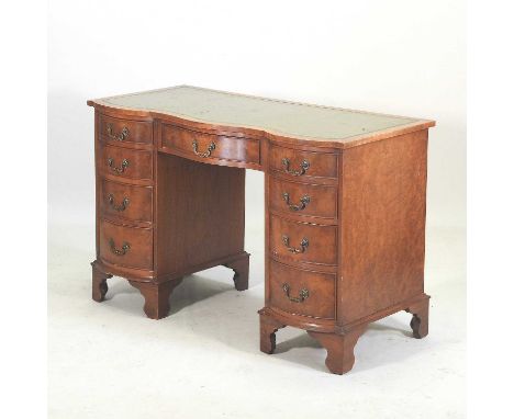 A mid 20th century walnut serpentine pedestal desk, with a green leather inset top, containing nine short drawers, on bracket