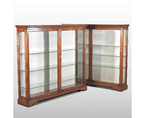 A pair of 20th century glazed oak dwarf display cabinets, each fitted with glass shelves and enclosed by a pair of bevelled g