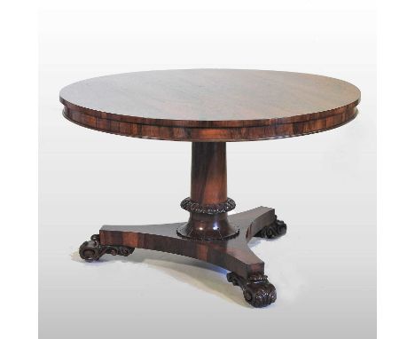 A Regency rosewood breakfast table, having a hinged circular top, on a tapered column, with lappet carved decoration, on a tr