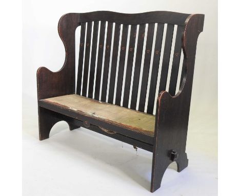 An Art Nouveau oak settle, in the manner of the Glasgow School, the slatted back with geometric inlay, shaped sides and padde