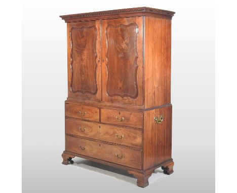 A George III mahogany linen press, with a Greek key cornice, enclosed by a pair of wavy panelled doors, with drawers below, f