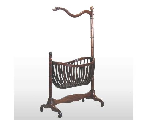 An unusual early 19th century carved mahogany child's cradle, having an oval swing basket, on ring turned supports, surmounte