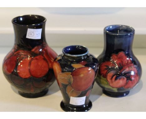 Three Moorcroft ceramic vases, tube lined and painted with floral/fruit decoration on blue grounds, factory marks to bases, t