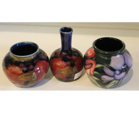 Three Moorcroft ceramic vases, each with floral/fruit tube lined and painted decoration, two blue and one green ground, facto