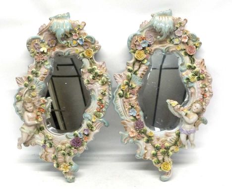 Pair of ornate late 19th century mirrors within ceramic holders, moulded with flowers and cherubs, the porcelain Continental 