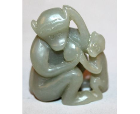 A CHINESE CELADON GREEN JADE GROUP OF A MONKEY, holding a peach and in the company of its young, 1.75in high. 