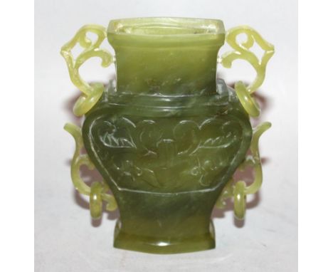 A CHINESE GREEN JADE VASE, of rectangular section and archaic form, the sides unusually set with two pairs of scroll and loos