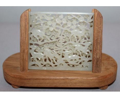 A CHINESE CARVED & PIERCED WHITE JADE TABLET, together with a wood display stand, the rectangular tablet carved to one side w