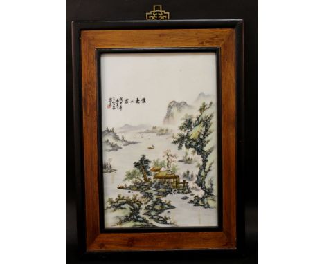 A CHINESE FRAMED PORCELAIN PLAQUE, decorated with calligraphy and a river landscape scene, the frame 20in x 14.2in, the plaqu