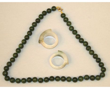 A GREEN JADE-LIKE NECKLACE, composed of spherical beads, 16.5in long; together with two jade-like rings. (3) 