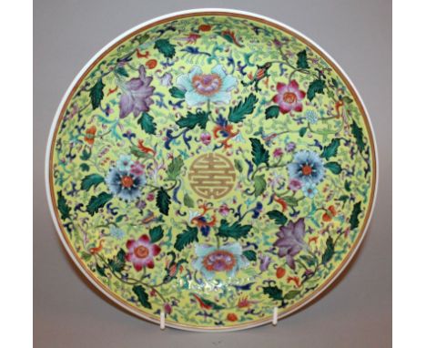 A GOOD QUALITY CHINESE FAMILLE ROSE YELLOW-GROUND PORCELAIN DISH, decorated with scroll and leaf stemmed flowerheads enclosin