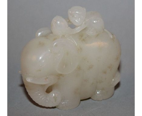 A CHINESE WHITE JADE CARVING, of a monkey with a peach lying on top of an elephant, the stone with pale brown inclusions, 2.2