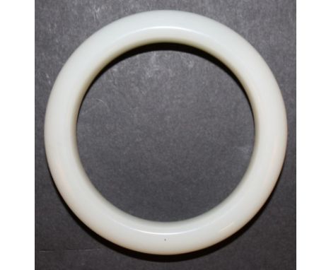 A CHINESE WHITE JADE-LIKE BANGLE, possibly glass, 3.1in diameter, the inner rim 2.25in diameter. 