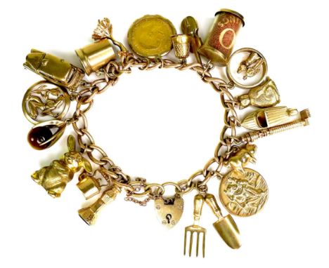 A 9ct yellow gold charm bracelet, kerb link with heart padlock clasp, all links marked, fitted with twety mostly 9ct yellow g