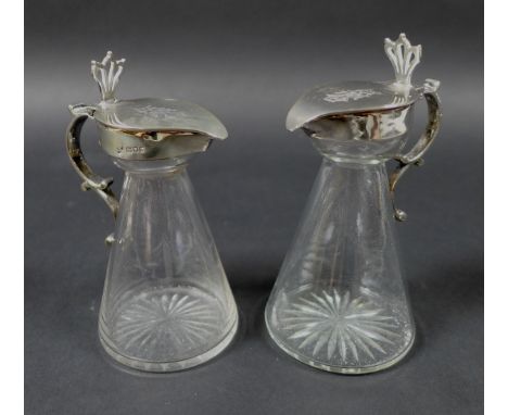 A pair of Edwardian clear glass and silver mounted noggin flasks, each of tapering form with mounted hinged lid, spout and th