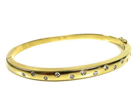An 18ct gold and diamond bangle, set with thirteen graduated brilliant cut stones, hinge clasp, 6cm across inside, 21g, with 