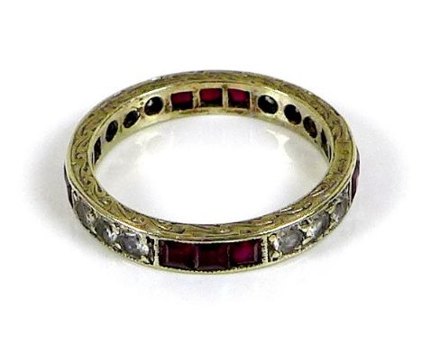 A 9ct white gold, ruby and paste eternity ring, the scroll engraved band set with twelve round cut diamonds and twelve square