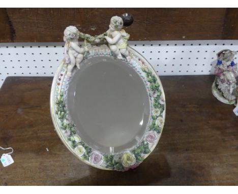 A late 19th century continental porcelain oval easel Mirror, the frame applied with roses and surmounted by cherubs, blue Sit